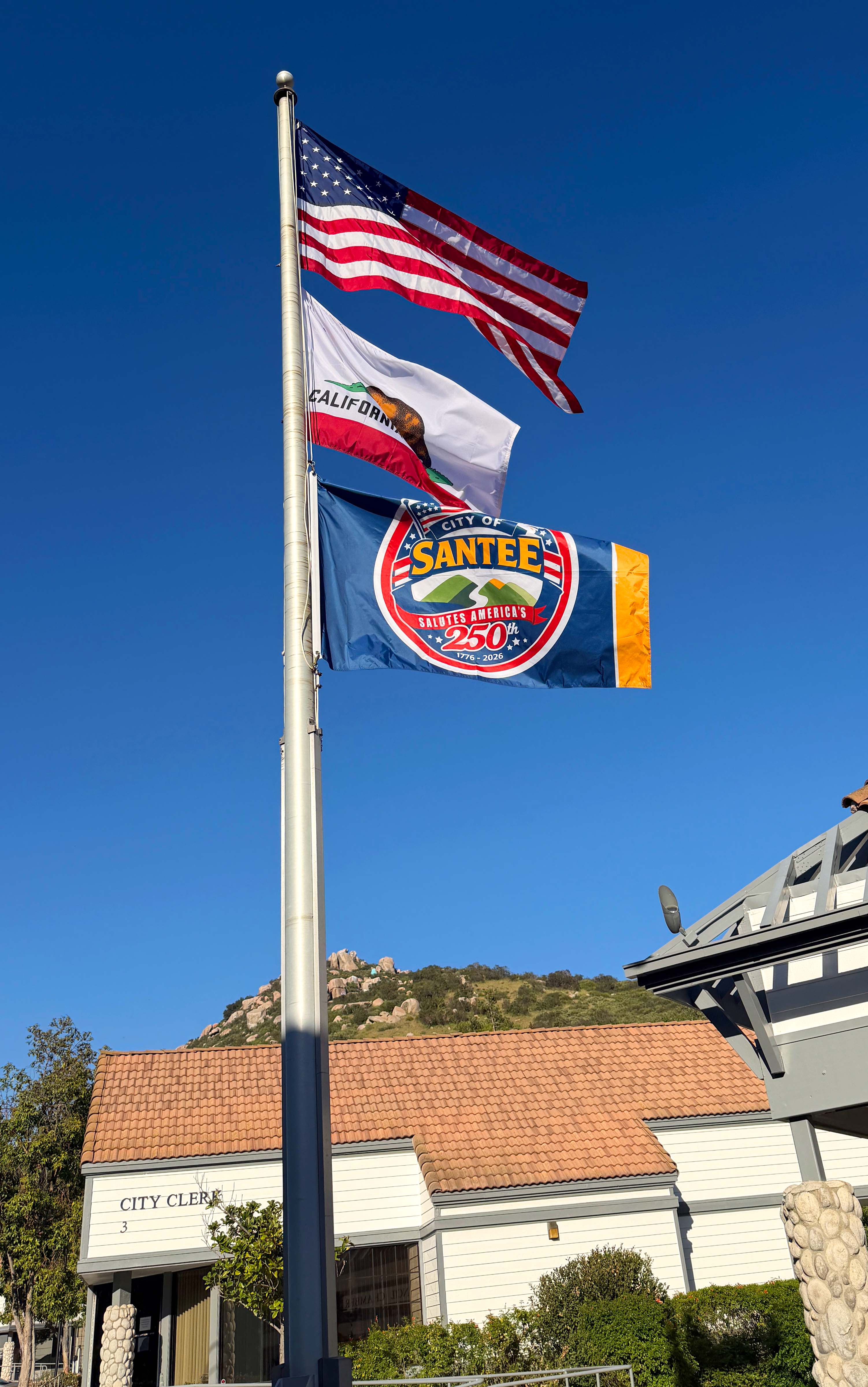 Flag pole with the American flag, State of California flag and the City of Santee's America 250th flag